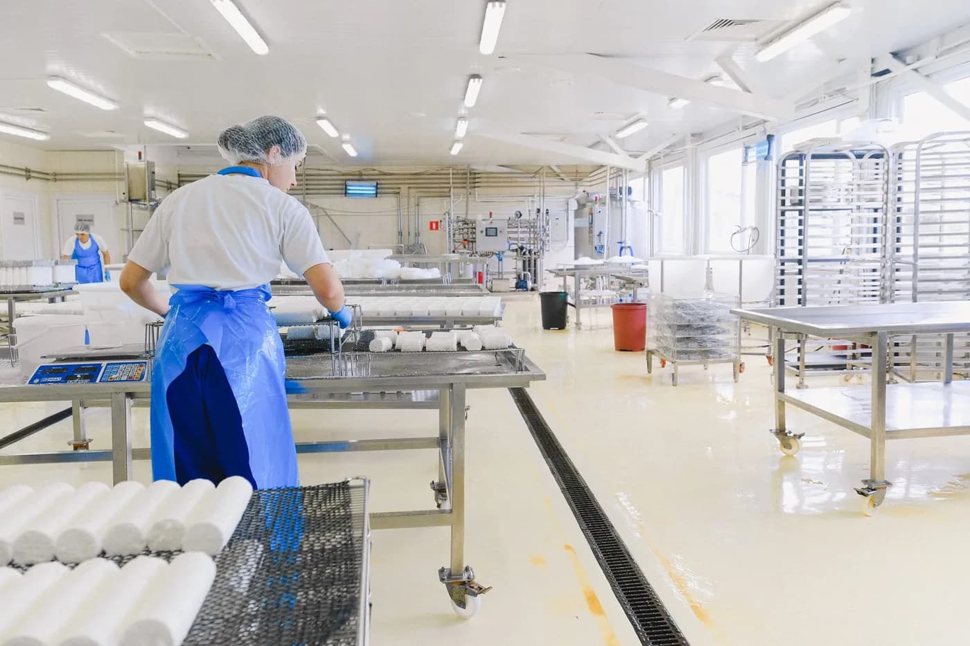 A worker in protective gear handling cheese in a dairy plant